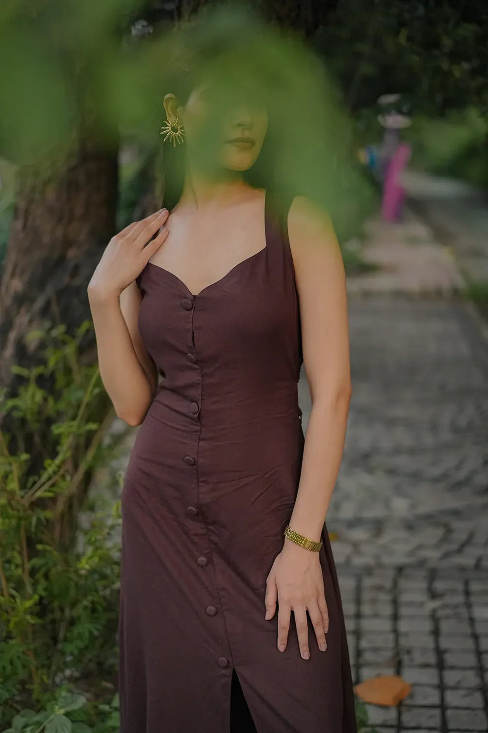 Woman in brown buttoned dress with gold bracelet and statement earring, outdoors, Streiq fashion