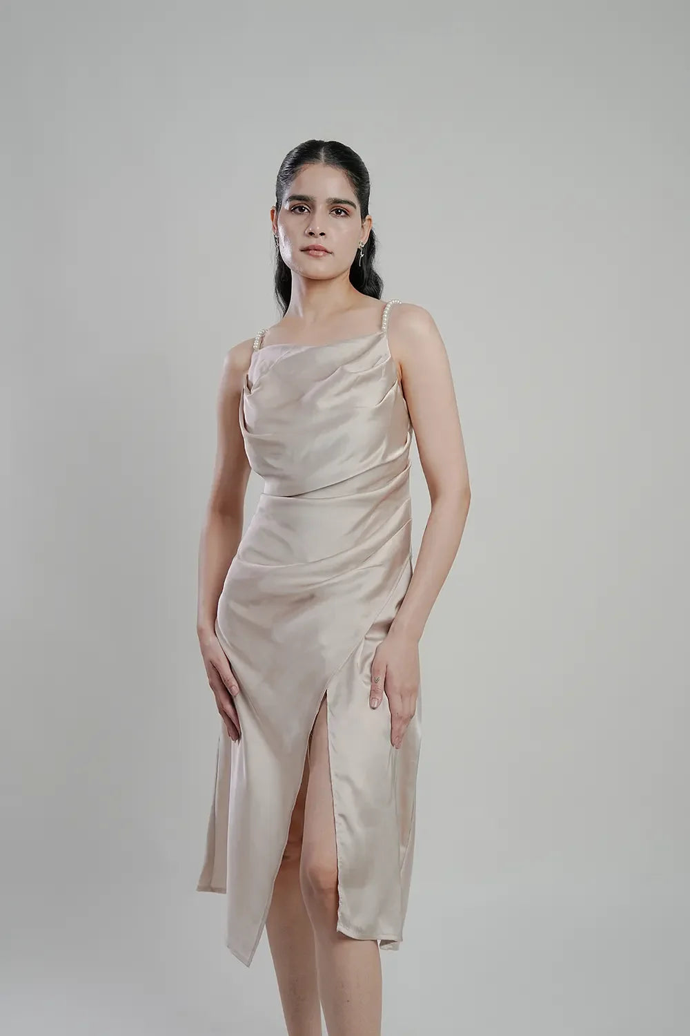 Woman in a champagne satin midi dress with pearl straps and front slit, Streiq fashion