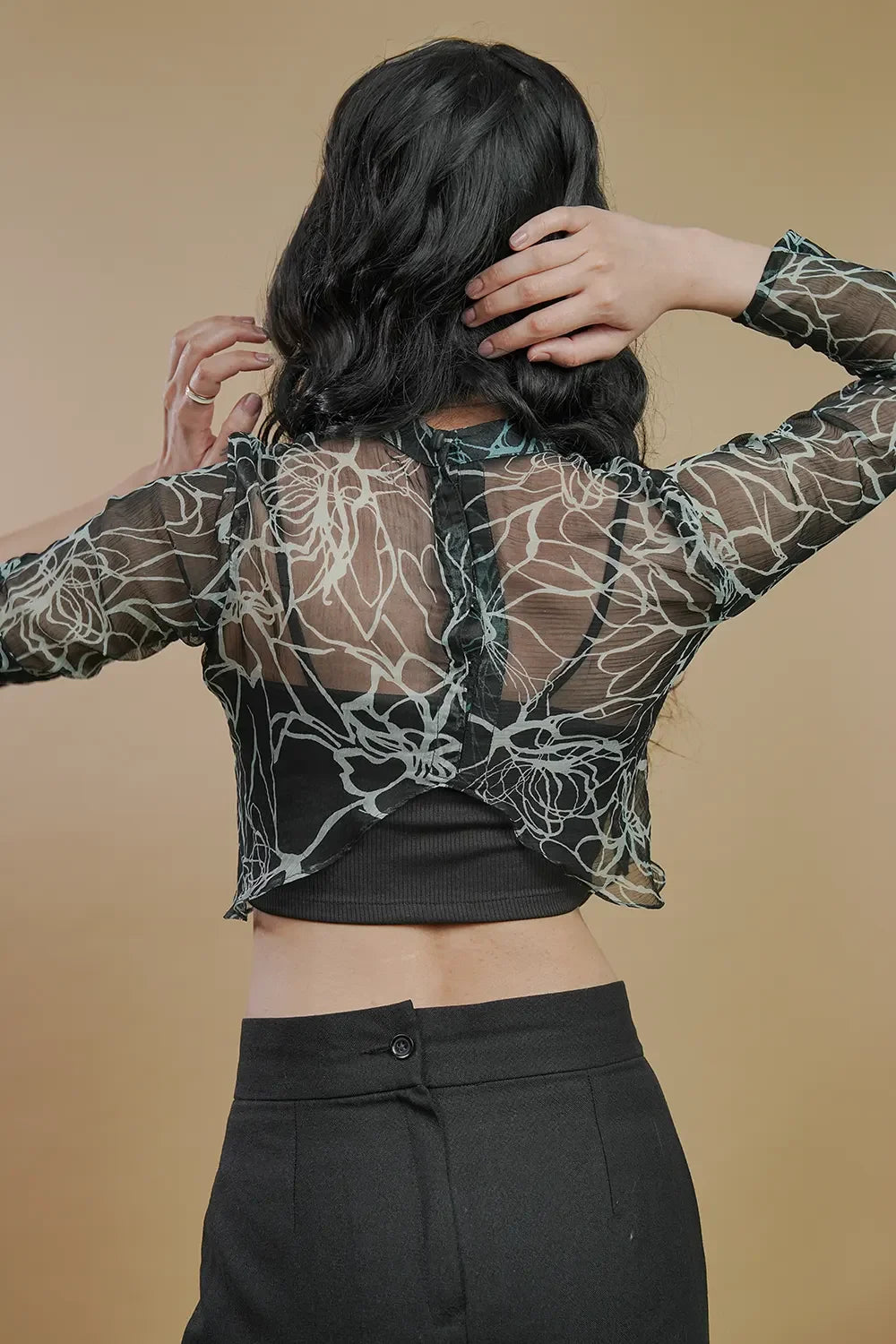 Back view of woman in sheer floral mesh top and black pants, Streiq fashion style