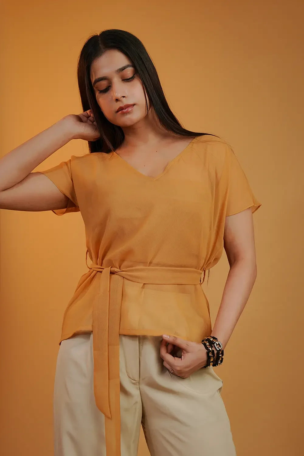 Woman in a mustard yellow belted top and beige pants, stylish fashion by Streiq