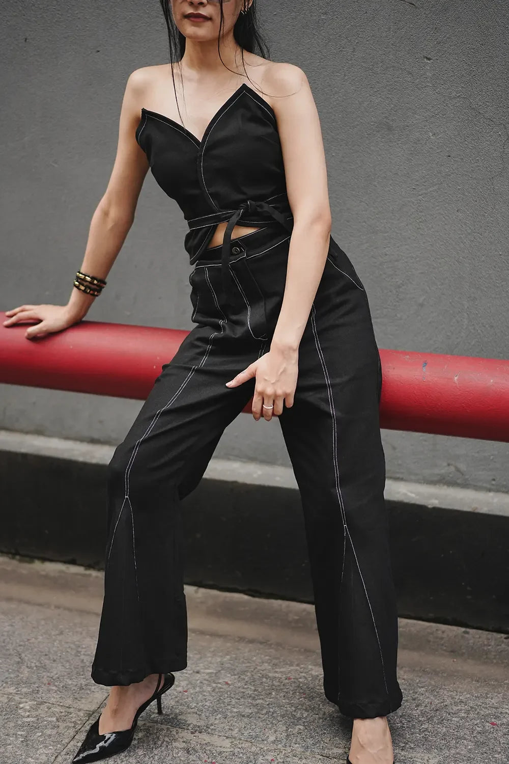 Woman modeling black sleeveless jumpsuit with white stitching, street style fashion, Streiq