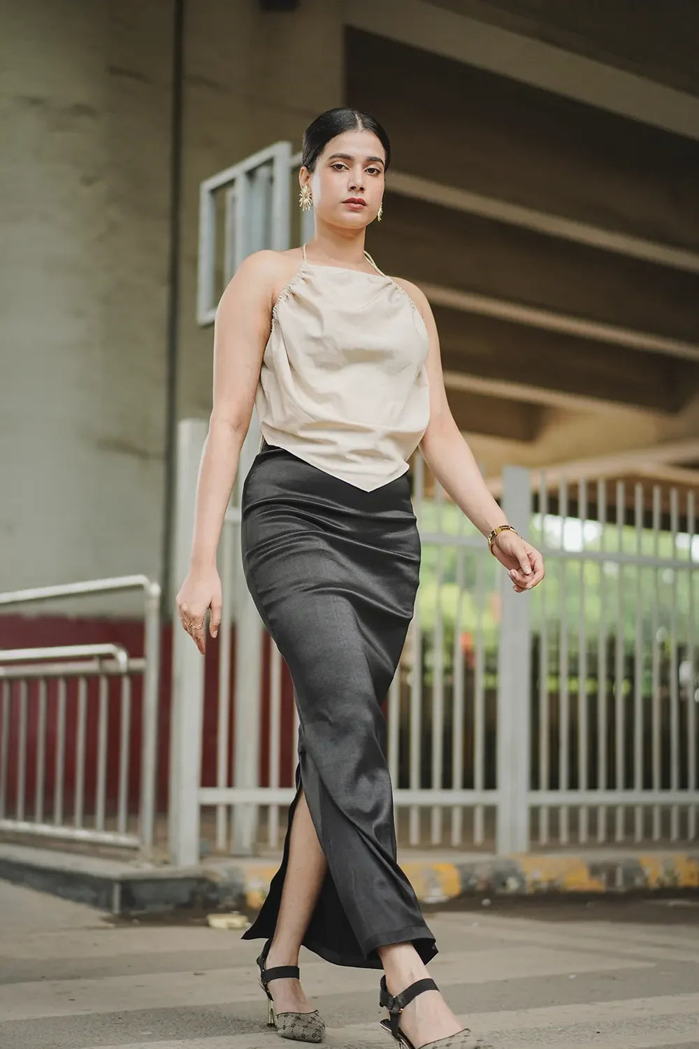 Woman in elegant beige top and black satin skirt walking confidently outdoors, Streiq fashion