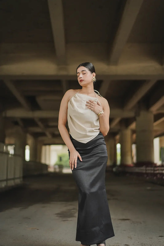 Woman in a satin top and black skirt posing under an urban bridge, Streiq fashion style