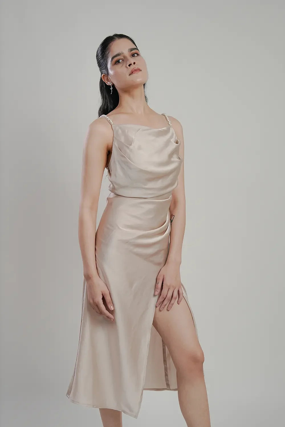 Woman modeling a sleeveless beige satin dress with pearl straps, Streiq fashion style