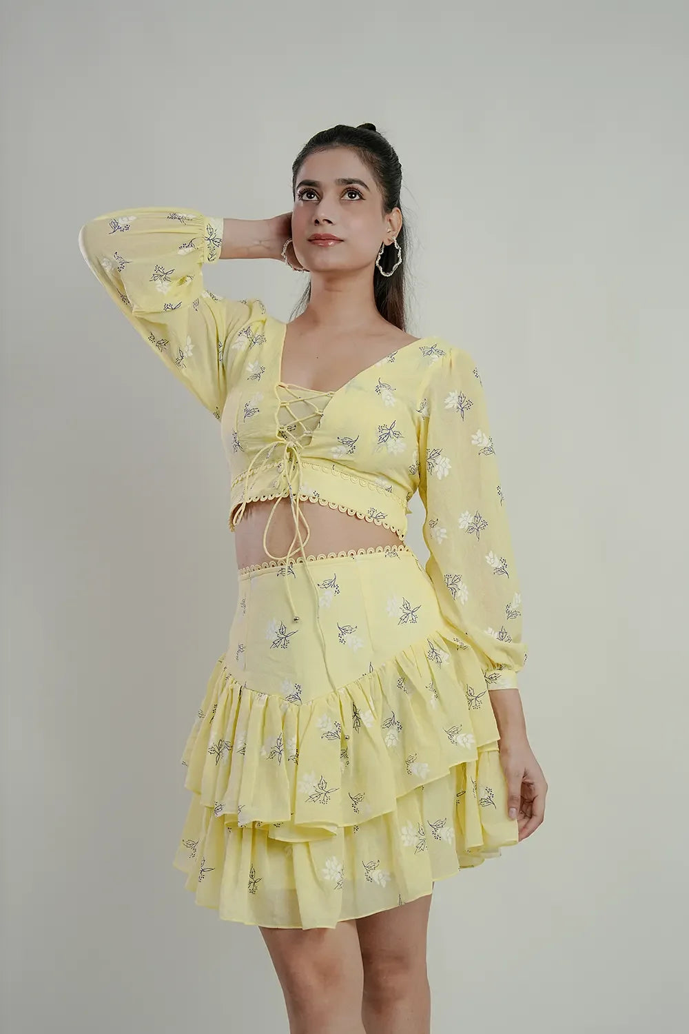 Woman in a light yellow floral two-piece set with lace-up crop top and layered skirt, Streiq fashion