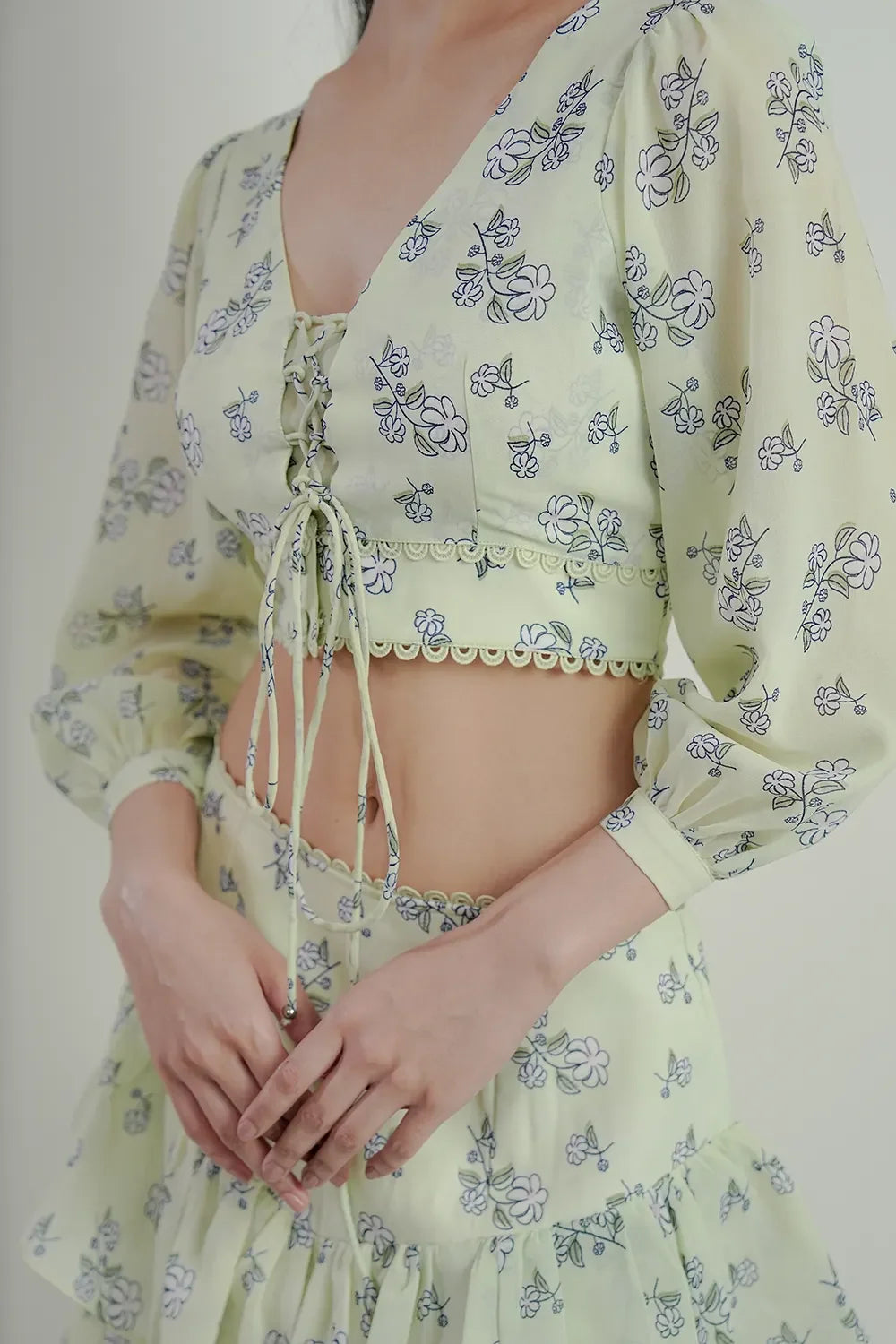 Woman wearing light yellow floral lace-up crop top and skirt set from Streiq