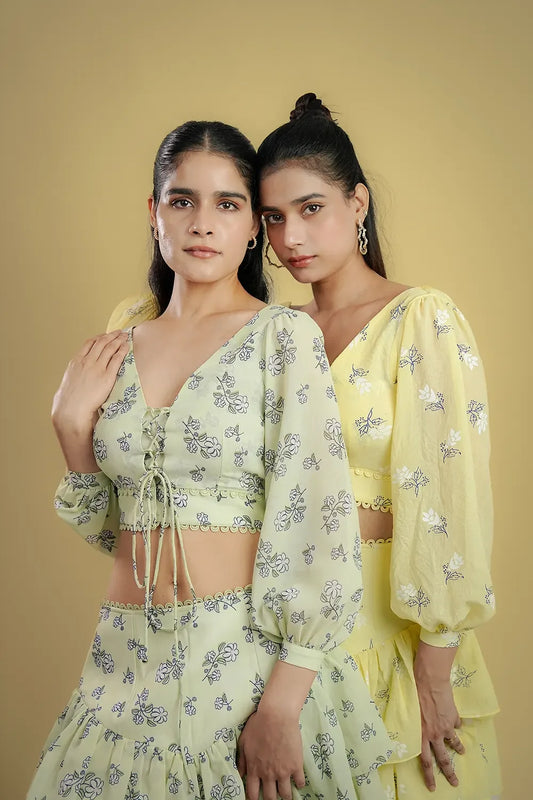 Two women in floral print pastel outfits from Streiq, posing against a plain beige background.