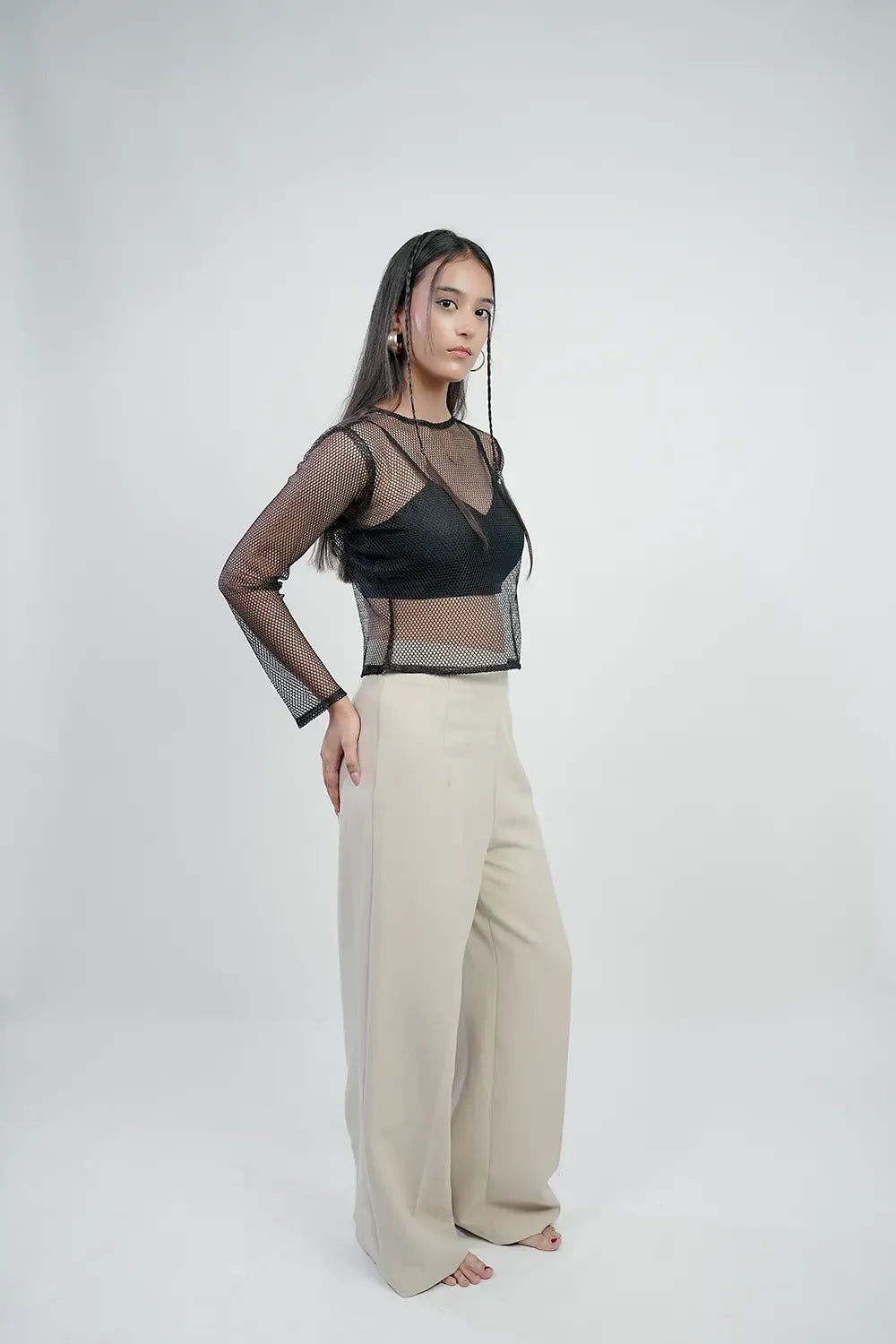 Woman in a black mesh long-sleeve top and beige wide-leg pants on white background, Streiq fashion