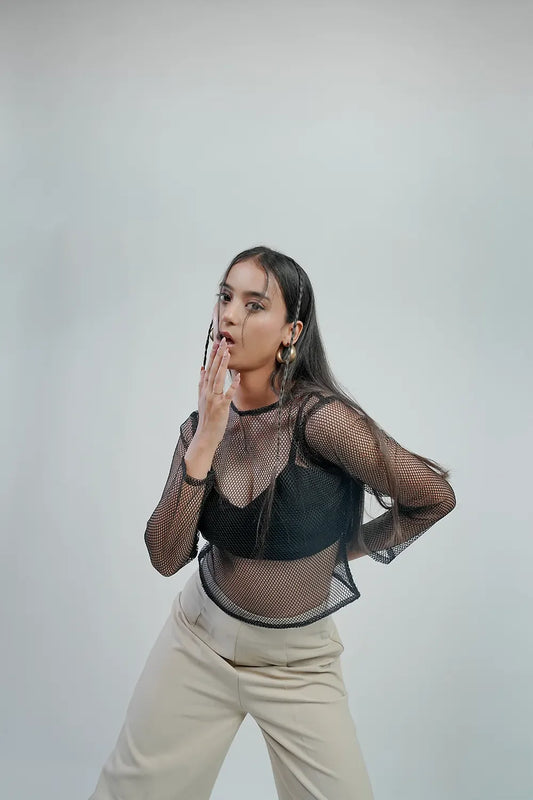 Woman in black mesh top and beige pants posing for Streiq Uniquely You fashion homepage