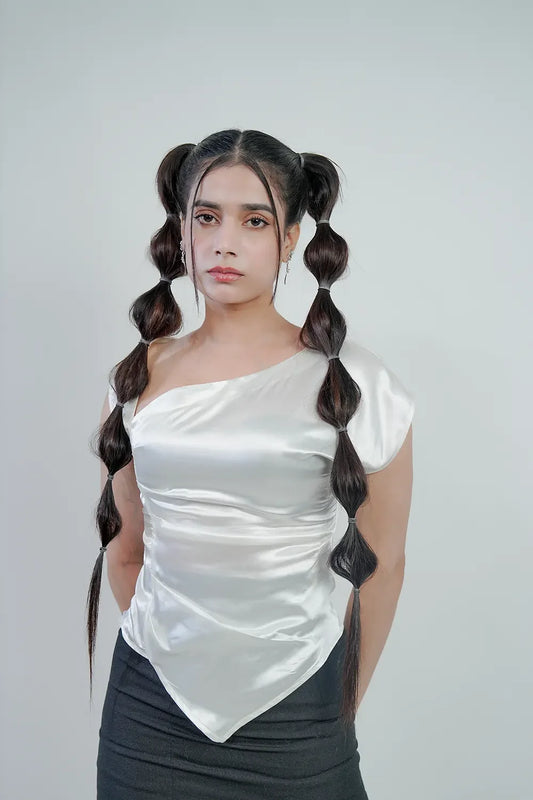 Woman in a white satin one-shoulder top and unique bubble ponytail hairstyle, Streiq fashion