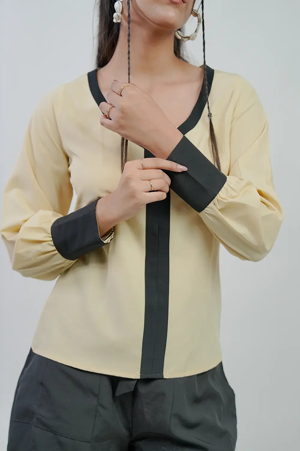 Woman wearing a beige and black long sleeve blouse from Streiq, minimalist modern style
