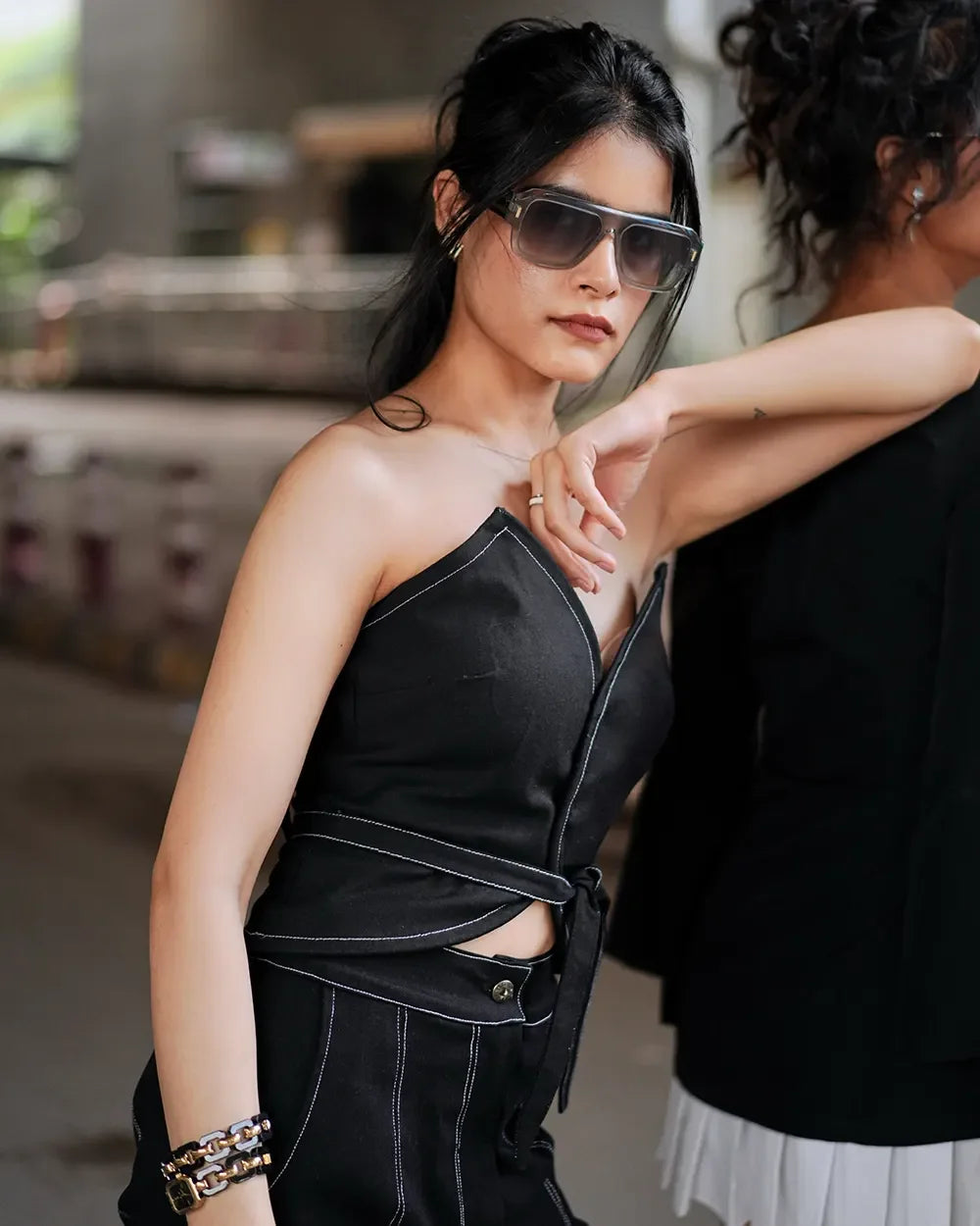 Stylish woman in black top and sunglasses posing with confidence, modern fashion look